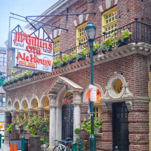 The front facade of McGillin's Olde Ale House in downtown Philadelphia. It's an old brick building with a large neon sign.