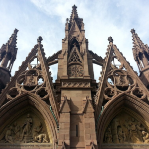 A photo of the very large front gate of the Green-Wood Cemetery, taken from below so the sky is above the spires.