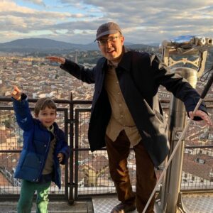 Writer Andrew Leland and his son smiling on top of a dome in Italy.