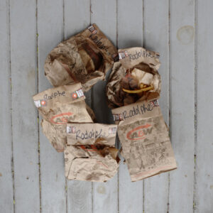 A photo of a pile of crumpled takeout bags. You can make out the name "Rodolphe" written on most of the bags. One of them is torn open and a few french fries are sticking out.
